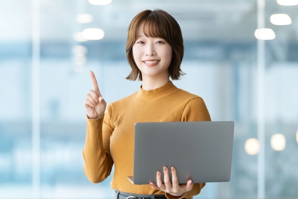 女性がパソコンを持って指さす